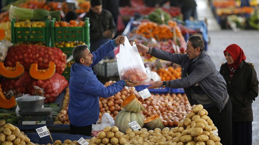 A vendor sells potatoes and other vegetables to a customer in an open market in central Ankara February 5, 2014. The humble potato has become a factor in Turkey's political and economic turmoil as prices of the staple soar, hurting the living standards of poorer Turks just before the ruling AK Party's toughest election test in a decade. At a market in the lower-income Istanbul suburb of Kucukcekmece, potatoes sell for between 3 and 4 lira ($1.33 and $1.77) a kilogramme, up from slightly more than 1 lira at 