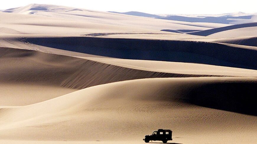 A four wheel drive vehicle crosses the sand dunes in the late afternoon sun near Egypt's western desert oasis of Siwa on February 3, 2002. The oasis has about 230 hot and cold mainly fresh water springs, and several large lakes scattered around the area, which is popular for tourists on desert safari trips. - RTXL1ZG