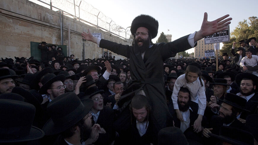 An Ultra-Orthodox Jewish man is carried on the shoulders by his friends in an "honor gesture" into the Jerusalem central police station on his way to prison, as tens of thousands of religious Israelis protested on June 17, 2010  against a Supreme Court ruling which ordered the jailing of a group of Ashkenazi parents of European origin who have refused to send their daughters to a school with Jewish girls of Middle Eastern, or Sephardic, descent. AFP PHOTO/MENAHEM KAHANA (Photo credit should read MENAHEM KAH