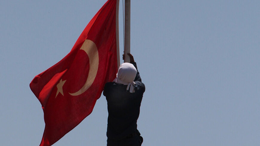 A masked Kurdish protestor try to pull down a Turkish flag on June 8, 2014 in Diyarbakir, eastern Turkey, after a man was killed during clashes with Turkish soldiers the night before in Lice. Two Kurdish protesters have died of gunshot wounds sustained during fierce clashes with Turkish soldiers in the country's southeast on June 7. Three people, including two soldiers, were hospitalised after the demonstrators opened fire, hurled stones and fireworks at security forces, according to an AFP reporter on the 