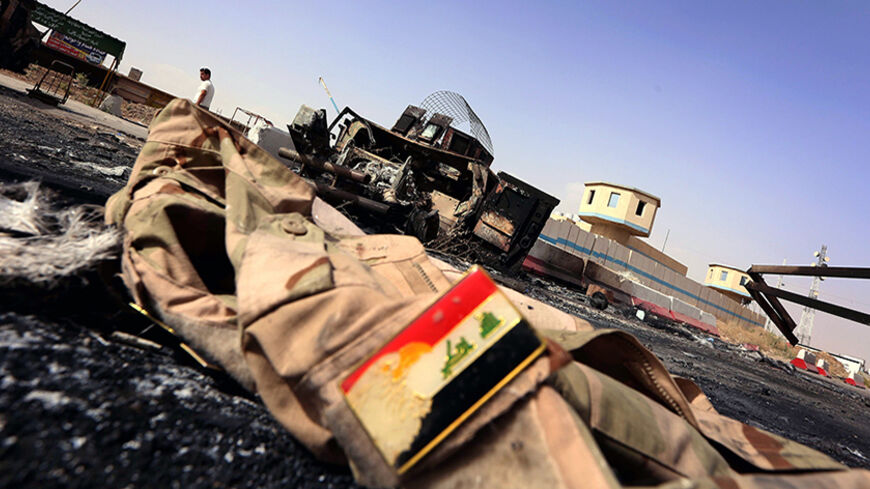 The jacket belonging to an Iraqi Army uniform lies on the ground in front of the remains of a burnt out Iraqi army vehicle close to the Kukjali Iraqi Army checkpoint, some 10km of east of the northern city of Mosul, on June 11, 2014, the day after Sunni militants, including fighters from the Islamic State of Iraq and the Levant (ISIL) overran the city.  Half a million people were estimated to have fled Iraq's second largest city, as Islamist militants tightened their grip after overrunning it and a swathe o