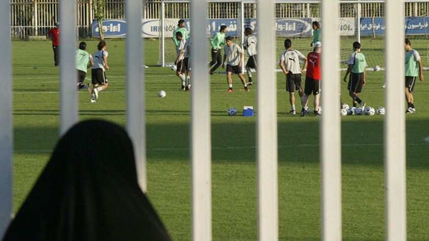 Tehran, IRAN:  An Iranian woman watches a training session of Iran's national football team from behind a fence as females were not allowed to enter the stadium at Tehran's Azadi (Freedom) sport complex, 22 May 2006. Iran's supreme leader has vetoed an order by President Mahmoud Ahmadinejad to end a 26-year-old ban on allowing women in stadiums for major sporting events, the government said earlier this month. Last month Ahmadinejad ordered an end to a decades-old ban on women entering stadiums for major sp