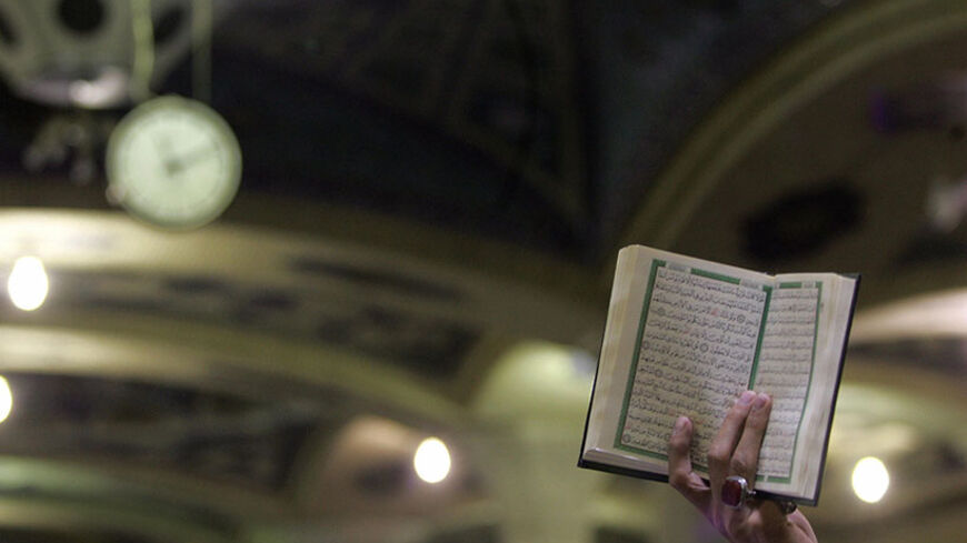 QOM, IRAN:  An Iranian Muslim cleric holds a copy of the Holy Koran during a sit-in condemning Pope Benedict XVI's recent speech about Islam and holy war in the auditorium of the Feyzieh, the main seminary school in Iran's clerical epicentre of Qom, 130 kms (80 miles) south of Tehran, 17 September 2006. Religious seminaries across Iran shut today to stage protests over remarks by the Pope that linked Islam to violence as top clerics vehemently criticised the pontiff's remarks. All of Iran's seminary schools