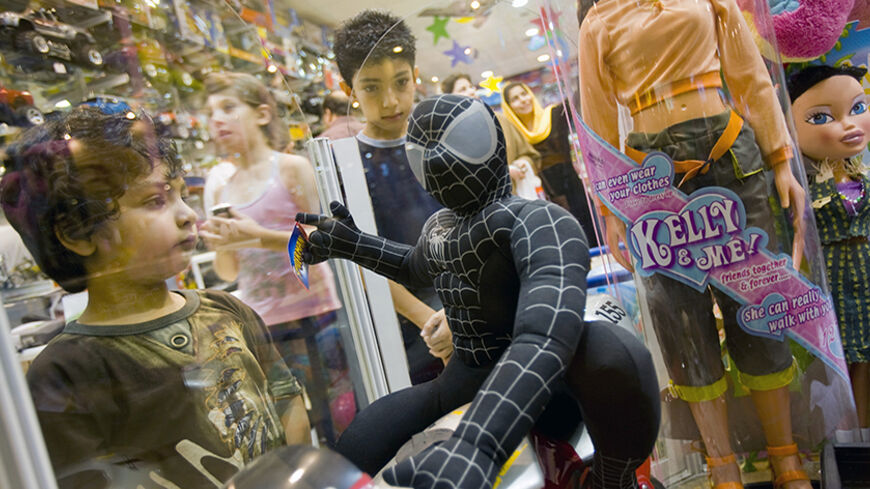 Iranian young boys look at a toy which depicts the character "Spiderman" at a shopping centre on the island of Kish in the Persian Gulf 1250 km (777 miles) south of Tehran August 4, 2008. Kish became the country's first free trade zone and the new gateway to Iran in 1982, being 17 km (11 miles) off the southern shore of mainland Iran. REUTERS/Morteza Nikoubazl (IRAN) - RTR20MIF