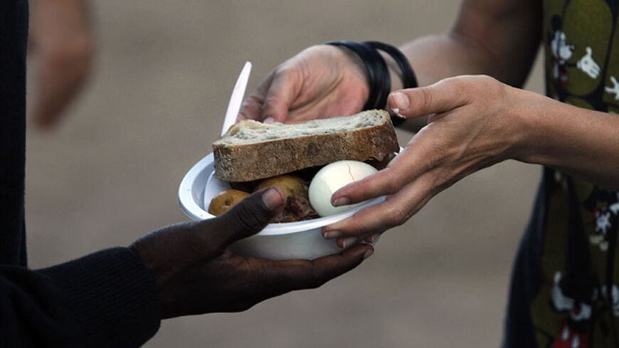 An African migrant receives food from a volunteer at Levinsky park in South Tel Aviv June 6, 2012. About 60,000 Africans have crossed into Israel across its porous border with Egypt in recent years. Israel says the vast majority are job seekers, disputing arguments by humanitarian agencies that they should be considered for asylum. Picture taken June 6, 2012. REUTERS/Baz Ratner (ISRAEL - Tags: SOCIETY IMMIGRATION FOOD) - RTR33VHG