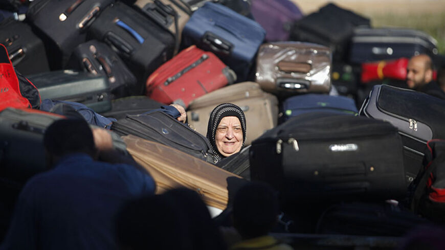 A Palestinian passenger, hoping to cross into Egypt, searches for her bag as she waits at the Rafah crossing, between Egypt and the southern Gaza Strip, September 30, 2013. Egypt partially reopened its border crossing with the Gaza Strip for three days on Saturday for the humanitarian needs of patients seeking treatment, and students studying outside of Gaza, a Palestinian official said.  REUTERS/Ibraheem Abu Mustafa (GAZA - Tags: POLITICS SOCIETY IMMIGRATION TPX IMAGES OF THE DAY) - RTR3FFFU
