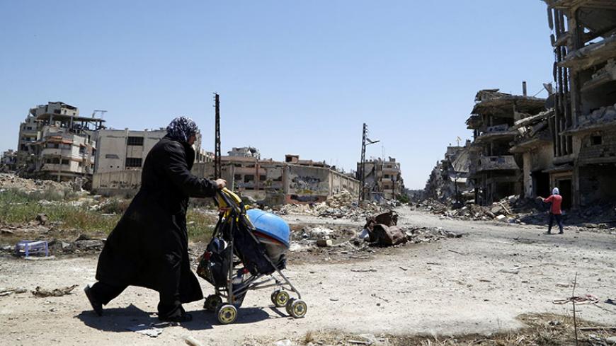 A woman pushes a baby's stroller loaded with belongings recovered from her home in the Wadi Al-Sayeh district at the al-Khalidiyeh area in Homs May 14, 2014. The fall of Syria's third largest city to government forces is a major blow to the opposition and a boost for Assad, weeks before his likely re-election. Picture taken May 14, 2014. REUTERS/Omar Sanadiki (SYRIA - Tags: CIVIL UNREST CONFLICT) - RTR3PD8B