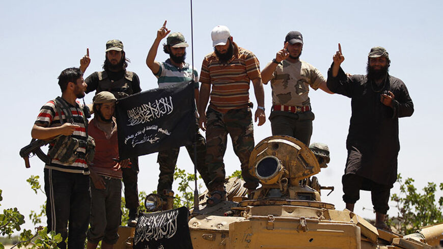 Islamist Syrian rebel group Jabhat al-Nusra members gesture while posing on a tank on Al-Khazan frontline of Khan Sheikhoun, northern Idlib province May 17, 2014. REUTERS/Hamid Khatib (SYRIA - Tags: CIVIL UNREST MILITARY POLITICS CONFLICT) - RTR3PM9N
