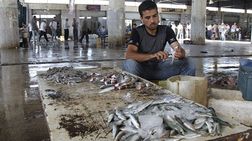 A fishmonger cleans fish at a wet market in Latakia city May 25, 2014. REUTERS/Khaled al-Hariri (SYRIA - Tags: FOOD BUSINESS EMPLOYMENT) - RTR3QRGH