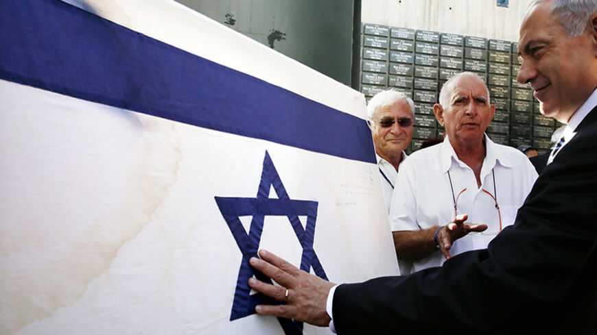 Israeli Prime Minister Benjamin Netanyahu touches the original flag Israeli paratroopers waved at the Western Wall during the 1967 Middle East War, before a special cabinet meeting marking Jerusalem Day at Ammunition Hill in Jerusalem May 28, 2014. Jerusalem Day marks the anniversary of Israel's capture of the Eastern part of the city during the 1967 Middle East War. In 1980, Israel's parliament passed a law declaring united Jerusalem as the national capital, a move never recognised internationally. REUTERS