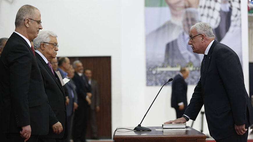 Palestinian Foreign Minister Riyad al-Maliki (R) takes his oath of office in front of Palestinian President Mahmoud Abbas during a swearing-in ceremony of the unity government, in the West Bank city of Ramallah June 2, 2014. Abbas swore in a unity government on Monday after overcoming a last-minute dispute with the Hamas Islamist group.
 REUTERS/Mohamad Torokman (WEST BANK - Tags: POLITICS) - RTR3RTFI