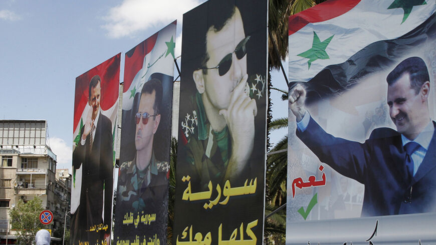 A woman walks past election posters of Syria's President Bashar al-Assad along a street in Damascus June 2, 2014. Buoyed by a sequence of victories over the past year, won in large part through Iran and Hezbollah, its Lebanese paramilitary proxy, Assad will be elected president this week for a third seven-year term, symbolically contested by selected opponents playing walk-on roles to pad out the main drama. To match Insight SYRIA-ELECTION/ASSAD    REUTERS/Khaled al-Hariri (SYRIA - Tags: POLITICS ELECTIONS 