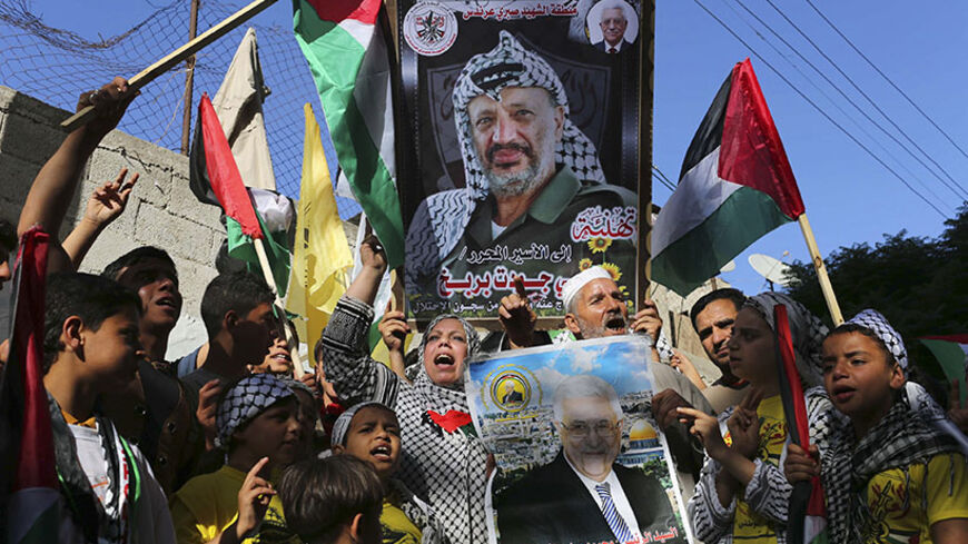 Palestinians hold pictures of late Palestinian leader Yasser Arafat (top) and Palestinian President Mahmoud Abbas as they celebrate the announcement of the unity government, in Khan Younis in the southern Gaza Strip June 2, 2014. President Mahmoud Abbas swore in a Palestinian unity government on Monday under a reconciliation deal with Hamas Islamists that led Israel to freeze U.S.-brokered peace talks with the Western-backed leader. REUTERS/Ibraheem Abu Mustafa (GAZA - Tags: POLITICS TPX IMAGES OF THE DAY) 