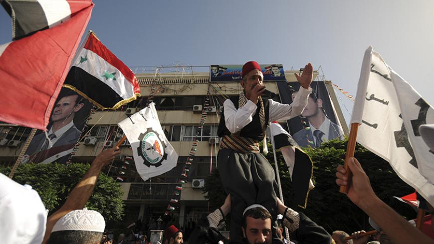 Supporters of Syria's President Bashar al-Assad wave the national flags and chant slogans in front of General Federation of Trade Unions building, during presidential election in Damascus June 3, 2014. Syrians began voting on Tuesday in an election expected to deliver an overwhelming victory to President Bashar al-Assad in the midst of a civil war that has fractured the country and killed more than 160,000 people. REUTERS/ Omar Sanadiki  (SYRIA - Tags: CIVIL UNREST POLITICS ELECTIONS) - RTR3RXFT
