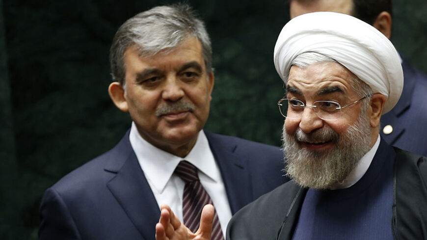 Iran's President Hassan Rouhani (R) greets the audience as he and his Turkish counterpart Abdullah Gul arrive at a meeting in Ankara June 10, 2014. REUTERS/Umit Bektas (TURKEY - Tags: POLITICS) - RTR3T167