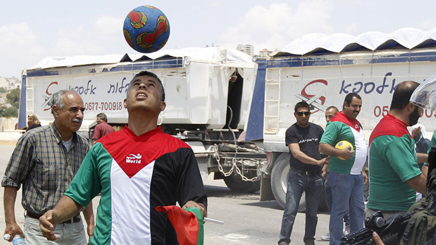 A Palestinian protester holding a Palestinian flag heads a soccer ball next to Israeli border police during a demonstration in solidarity with hunger-striking Palestinian prisoners held by Israel, outside Israel's Ofer military prison near Ramallah June 11, 2014. Israel's parliament has given initial approval to a law to enable the force-feeding of Palestinian prisoners on a hunger strike, drawing defiance from activists who said on Tuesday it would not deter the inmates.  REUTERS/Mohamad Torokman (WEST BAN