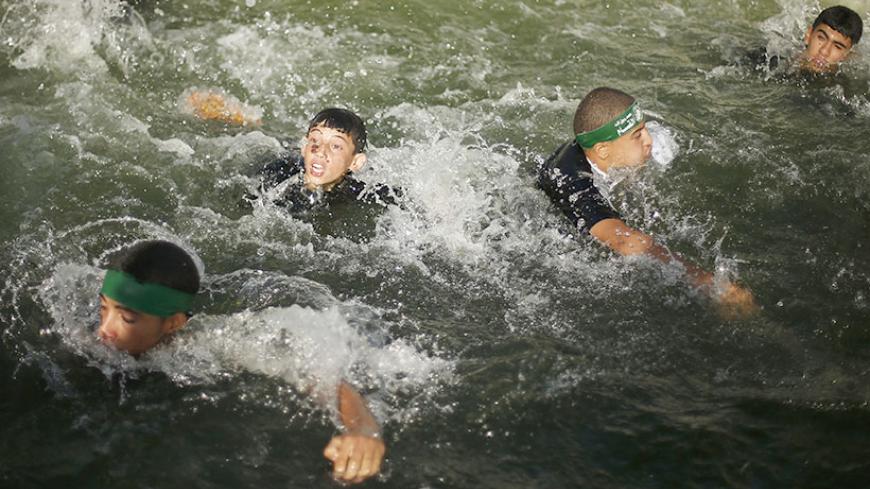 Young Palestinians swim in a pool as they take part in a military-style exercise at a summer camp organized by the Hamas movement in Gaza City June 12, 2014. Hamas stages dozens of military-style summer camps for young Palestinians in Gaza strip to prepare them to confront any possible Israeli attack, organisers said. REUTERS/Suhaib Salem (GAZA - Tags: POLITICS CIVIL UNREST) - RTR3TFW5