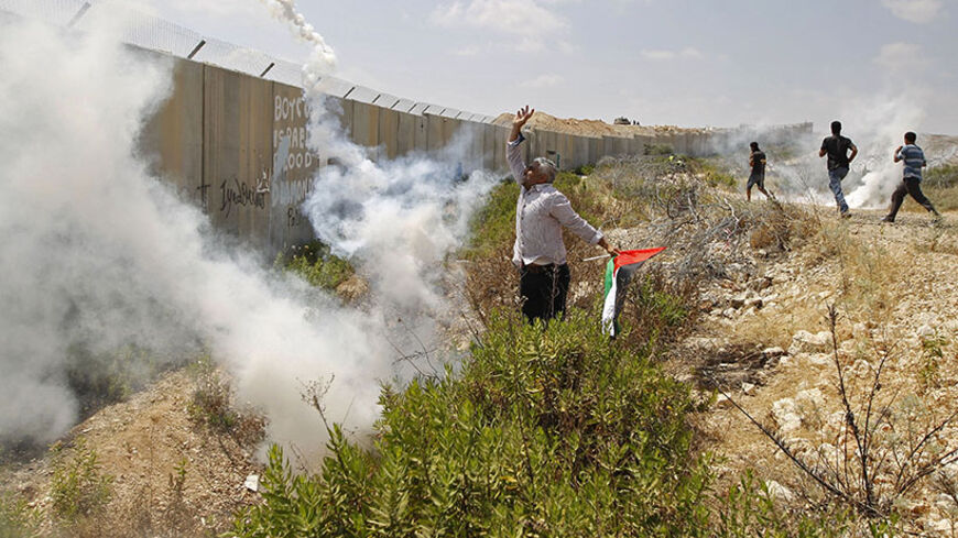 A Palestinian protester returns a tear gas canister fired by Israeli troops, during a protest in solidarity with hunger-striking Palestinian prisoners held by Israel, in the West Bank village of Bilin near Ramallah June 13, 2014. Some 120 Palestinians held by Israel began refusing food on April 24 in protest at their detention without trial. Since then the number has risen closer to 300. Israel's Prisons Service says 70 have been hospitalised. REUTERS/Mohamad Torokman (WEST BANK - Tags: POLITICS CIVIL UNRES