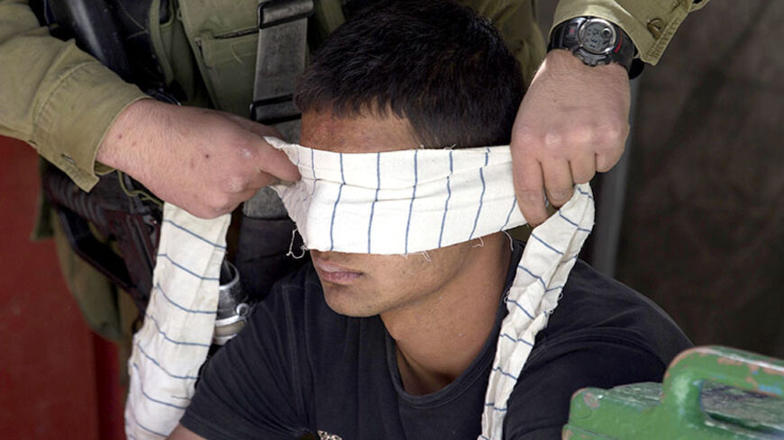 An Israeli soldier blindfolds of a Palestinian suspected of throwing stones as he detains him during clashes in the West Bank City of Hebron June 16, 2014. Israeli armed forces swept through half a dozen Palestinian towns on Monday and arrested more Hamas officials, expanding a search for three teenagers into a crackdown on the Islamist group accused of abducting them. Most of the military efforts have been concentrated in Hebron, a Hamas stronghold.   
REUTERS/Baz Ratner (WEST BANK - Tags: POLITICS CIVIL U