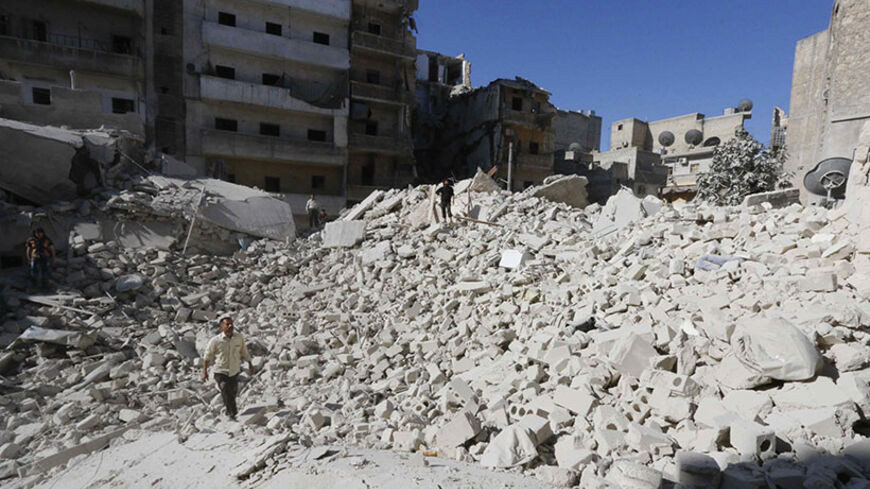 A man walks on debris of collapsed buildings at a damaged site hit by what activists said was a barrel bomb dropped by forces loyal to Syria's President Bashar al-Assad in Aleppo's al-Ansari neighbourhood June 18, 2014.  REUTERS/Hosam Katan (SYRIA - Tags: POLITICS CIVIL UNREST CONFLICT) - RTR3UEWE