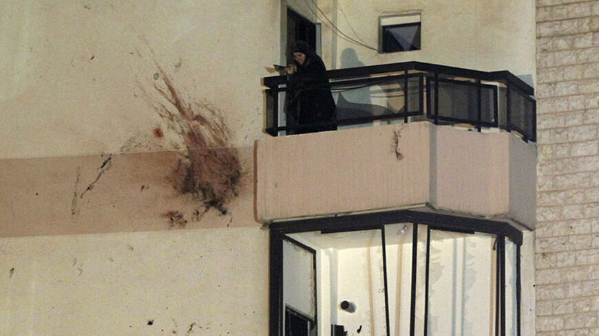 A woman stands on a balcony as she removes shattered glass beside bloodstains on the wall of a building at a site of an explosion in the southern suburbs of the Lebanese capital Beirut, early June 24, 2014. A suicide bomber blew up his car in southern Beirut on Monday night near an army checkpoint, killing himself and wounding several people watching the soccer World Cup in a nearby cafe. REUTERS/Mohamed Azakir (LEBANON - Tags: POLITICS CIVIL UNREST TPX IMAGES OF THE DAY) - RTR3VDDD