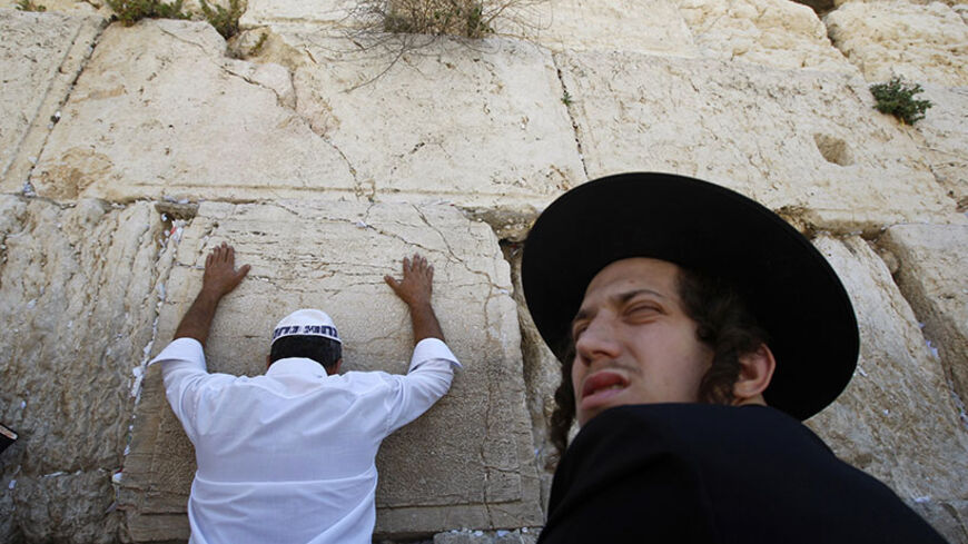 A Jewish worshipper prays as an ultra-Orthodox Jew sits in front of the Western Wall, Judaism's holiest prayer site, in Jerusalem's Old City May 28, 2009. On Thursday Jews mark Shavuot, the annual celebration of God's handing down of the Law (the Torah) to Moses at Mount Sinai in biblical times, according to Jewish tradition. REUTERS/Baz Ratner (JERUSALEM RELIGION) - RTXOVZB