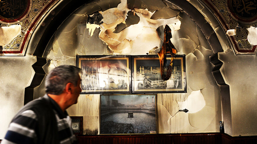 A man walks past burnt religious pictures at the Shiite Muhammediye Mosque on July 8 , 2014 in Istanbul after a fire took on early in the morning, causing considerable material damage, but leaving no one injured. The fire erupted in the Muhammediye Mosque, mostly attended by the Shiite Caferis in Istanbuls Esenyurt district, after the community received repeated threats over the last week. AFP PHOTO/OZAN KOSE        (Photo credit should read OZAN KOSE/AFP/Getty Images)