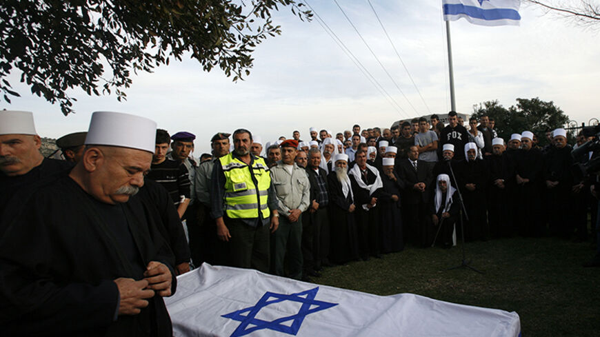 Elders of the community walk near the flag-draped coffin of Israeli soldier Ihab Chattib during his funeral in the northern Druze-Arab village of Maghar February 11, 2010. A Palestinian police officer stabbed and killed Chattib in the occupied West Bank on Wednesday, the military said, in an attack that could place more strain on U.S. efforts to revive Middle East peace talks. REUTERS/Gil Cohen Magen (ISRAEL - Tags: POLITICS CIVIL UNREST IMAGES OF THE DAY) - RTR2A3K6