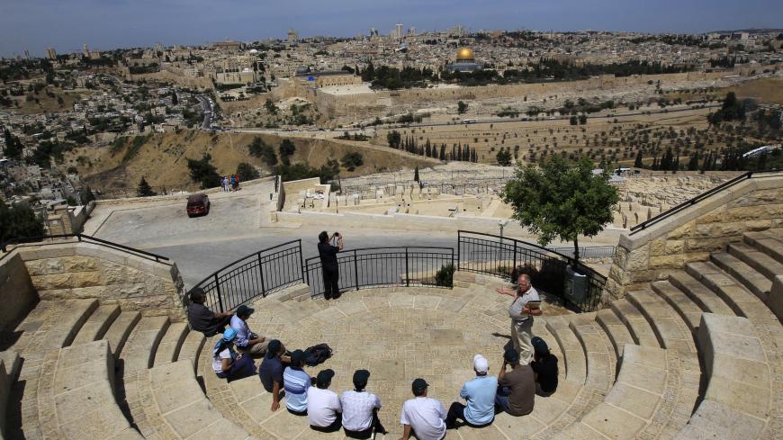Tourists sit at a lookout point on the Mount of Olives, overlooking Jerusalem's Old City May 25, 2011. The Dome of the Rock in Jerusalem's Old City is seen in the background. Palestinians and Israelis alike saw little prospect of a fresh start to Middle East peace talks on Wednesday after Israeli Prime Minister Benjamin Netanyahu's keynote speech to Congress. REUTERS/Ronen Zvulun (JERUSALEM - Tags: RELIGION TRAVEL) - RTR2MVI2