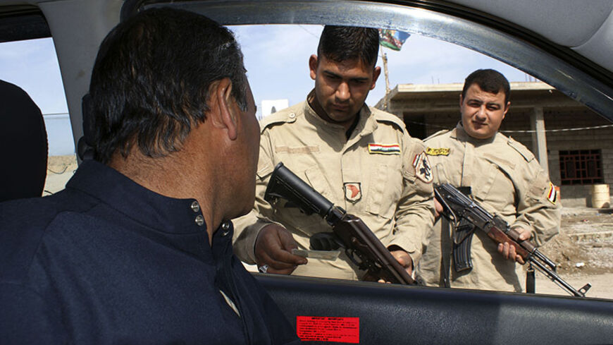 Members of the Awakening Council, a local neighbourhood guard unit, check the identification of a motorist at a security checkpoint in Diyala province February 10, 2013. Picture taken February 10, 2013. REUTERS/Mohammed Adnan (IRAQ - Tags: POLITICS) - RTR3DMLI