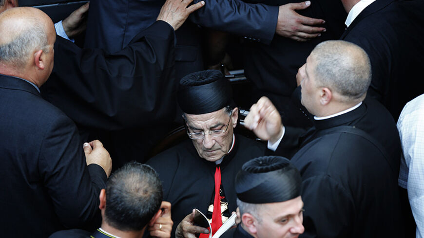 Maronite Patriarch Beshara al-Rai reads as he is surrounded by security personnel during his a visit to Birim, a northern Israeli village whose Maronite Christian residents were displaced 66 years ago May 28, 2014. The Lebanese church leader who defied warnings from the powerful Shi'ite Muslim Hezbollah movement by accompanying the Pope on a Holy Land visit pledged on Wednesday to help dispossessed Christians in Israel.  REUTERS/Finbarr O'Reilly (ISRAEL - Tags: RELIGION POLITICS TPX IMAGES OF THE DAY) - RTR