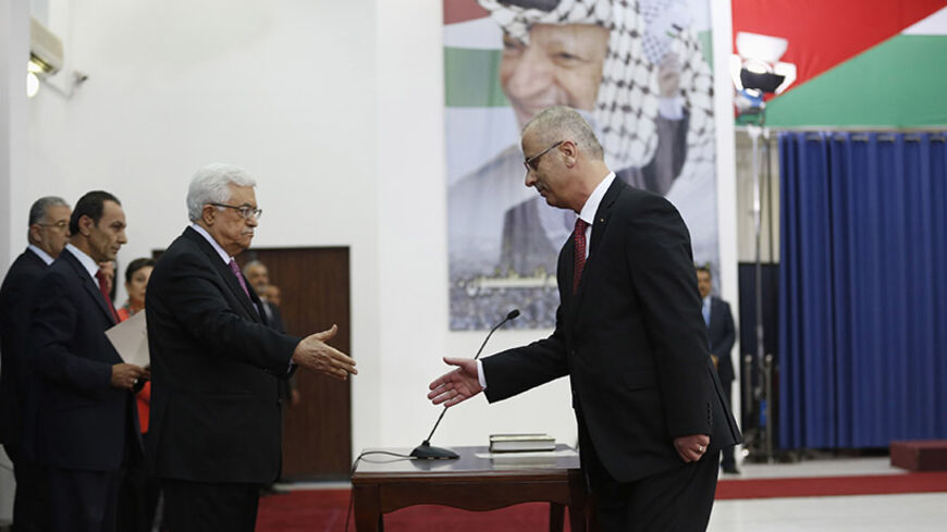 Palestinian Prime Minister Rami Hamdallah (R) shakes hands with Palestinian President Mahmoud Abbas during a swearing-in ceremony of the unity government, in the West Bank city of Ramallah June 2, 2014. Abbas swore in a unity government on Monday after overcoming a last-minute dispute with the Hamas Islamist group.
 REUTERS/Mohamad Torokman (WEST BANK - Tags: POLITICS) - RTR3RT5M