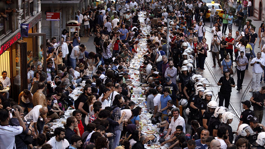 People prepare to break their fast on the first day of the holy month of Ramadan as police officers stand guard at near Taksim Square in Istanbul June 28, 2014. REUTERS/Osman Orsal (TURKEY - Tags: POLITICS CIVIL UNREST RELIGION) - RTR3W810