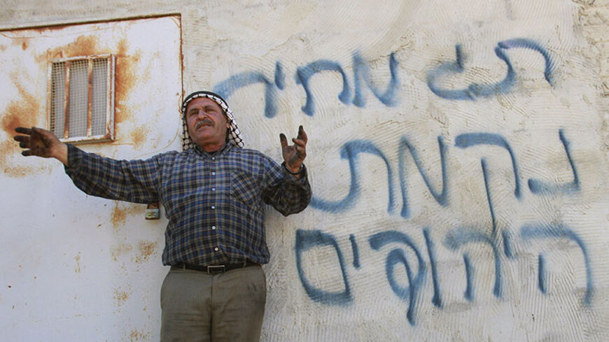 Palestinian farmer Basem Bani Jaber gestures to members of the media in front of Hebrew graffiti which Palestinians said was sprayed by Jewish settlers after burning his property in the West Bank village of Aqraba, near Nablus July 2, 2014. During so-called "Price Tag" incidents, mosques and Palestinian property are torched or damaged - a reference by ultranationalist Jews to making the government "pay" for any curbs on Jewish settlement on Palestinian land. The graffiti reads, "price tag" (top) and "Jewish