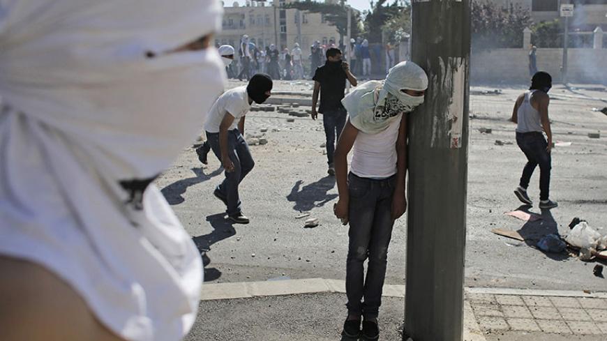 A Palestinian stone-thrower takes cover behind a street pole during clashes with Israeli police in Shuafat, an Arab suburb of Jerusalem, July 3, 2014. Israel faced a second day of violent Palestinian protests in Jerusalem on Thursday after the discovery of the body of a 16-year-old Palestinian boy on Wednesday in a forest near the city. Police clashed with a few dozen stone-throwing Palestinians in Shuafat, but the violence was on a much smaller scale than on Wednesday. REUTERS/Ammar Awad (JERUSALEM - Tags: