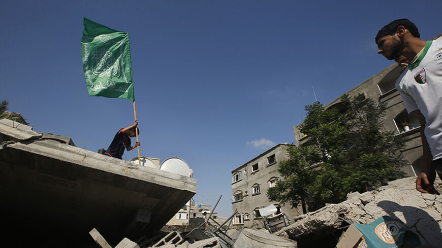 A Palestinian boy places a Hamas flag atop the rubble of a house which police said was destroyed in an Israeli air strike in the northern Gaza Strip July 9, 2014. At least 23 people were killed across Gaza, Palestinian officials said on Wednesday, by a bombardment Israel said may be just the start of a lengthy offensive against Islamist militants whose rockets struck deeper than ever before into Israel. REUTERS/Mohammed Salem (GAZA - Tags: POLITICS CIVIL UNREST) - RTR3XQSM