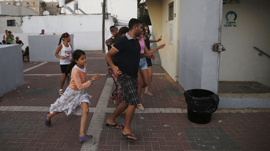 Israelis run towards a bomb shelter as a siren sounds warning of incoming rockets in the southern city of Ashkelon July 9, 2014. Israeli air strikes shook Gaza every few minutes on Wednesday, and militants kept up rocket fire at Israel's heartland in intensifying warfare that Palestinian officials said has killed at least 44 people in the Hamas-dominated enclave. REUTERS/Baz Ratner (ISRAEL - Tags: POLITICS CIVIL UNREST) - RTR3XVKO