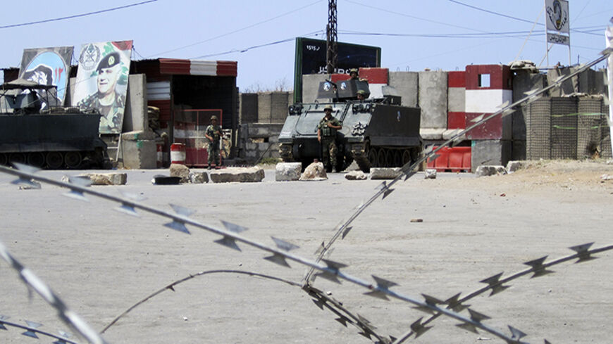 Lebanese Army soldiers patrol as relatives of Islamists held in a Lebanese jail block a street with barbed wire to express their solidarity with those jailed, and demand their release, after Friday prayers in Tripoli, northern Lebanon, July 11, 2014. REUTERS/Omar Ibrahim (LEBANON - Tags: POLITICS CIVIL UNREST) - RTR3Y698