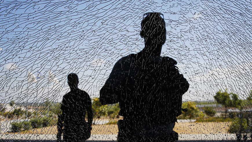 Israeli security personnel look at a window damaged by shrapnel after a short-range rocket landed on Tuesday near the Erez crossing July 16, 2014. An Israeli civilian was killed by the rocket fired from the Gaza Strip on Tuesday, the military said, the first Israeli fatality in more than a week of fighting with Palestinian militants. The Islamist group Hamas that rules Gaza claimed responsibility for launching the short-range rocket that struck an area along the border with Gaza. REUTERS/Finbarr O'Reilly (I