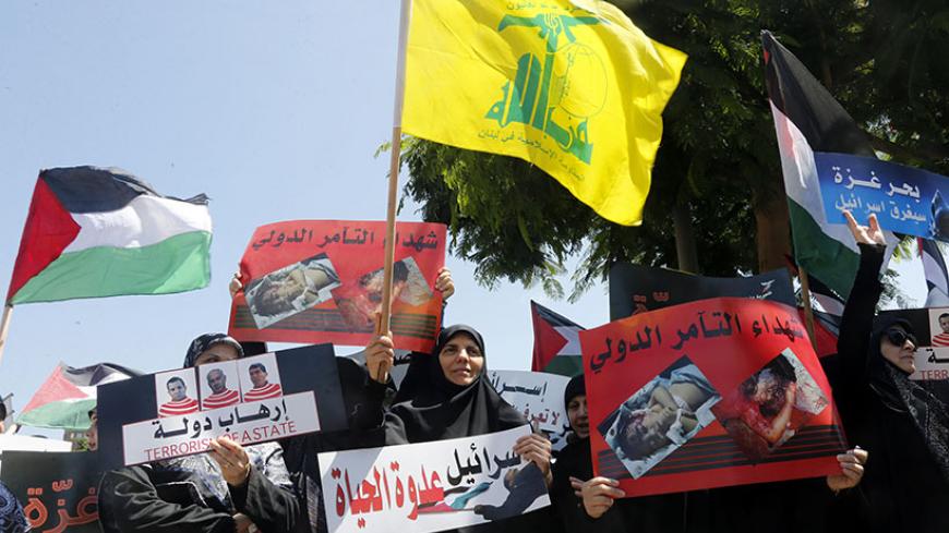 Lebanon's Hezbollah supporters hold banners and wave Hezbollah (C) and Palestinian flags (L) during a demonstration against Israel's military action in Gaza, in front of the United Nations headquarters in Beirut July 18, 2014. Israel stepped up its land offensive in Gaza with artillery, tanks and gunboats on Friday and declared it could "significantly widen" an operation Palestinian officials said was killing ever greater numbers of civilians. Israeli gunboats lit up the sky with their fire before dawn whil
