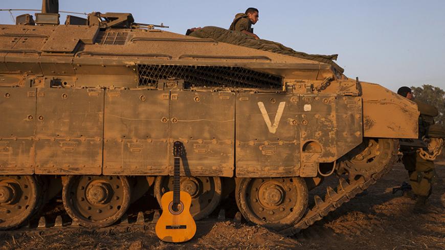 A guitar leans on an armoured personnel carrier (APC) that Israeli soldiers are sleeping on top of near the border with Gaza July 30, 2014. Israeli fire killed at least 43 Palestinians in the Gaza Strip early on Wednesday as the Jewish state said it targeted Islamist militants at dozens of sites across the coastal enclave, while Egyptian mediators prepared a revised ceasefire proposal. REUTERS/Baz Ratner (ISRAEL - Tags: CIVIL UNREST CONFLICT MILITARY POLITICS TPX IMAGES OF THE DAY) - RTR40M4J