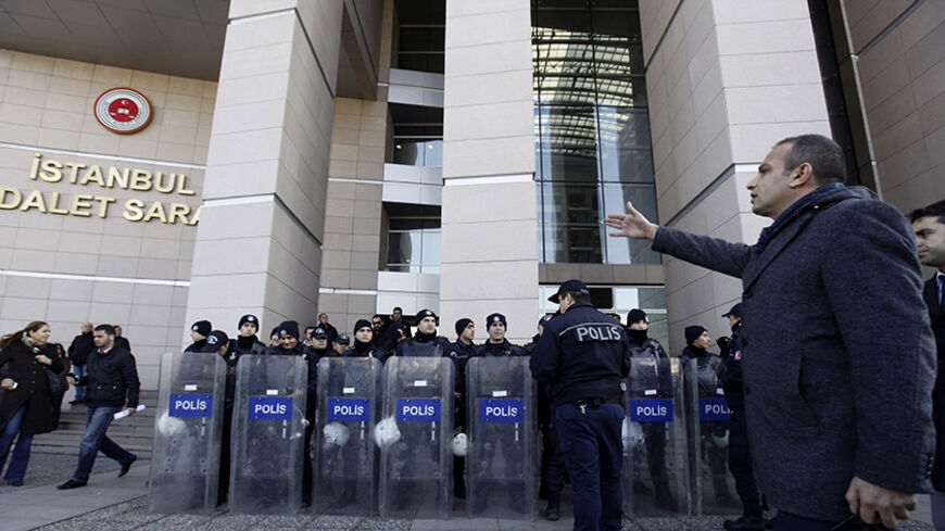 A plainclothes police officer reacts as riot police stand guard in front of the courthouse in Istanbul December 20, 2013. Turkish police arrested eight people in connection with allegations of official corruption and bribery, a newspaper said on Friday, in an investigation Prime Minister Tayyip Erdogan has called a "dirty operation" aimed at undermining his rule. REUTERS/Osman Orsal (TURKEY - Tags: POLITICS CRIME LAW) - RTX16PID