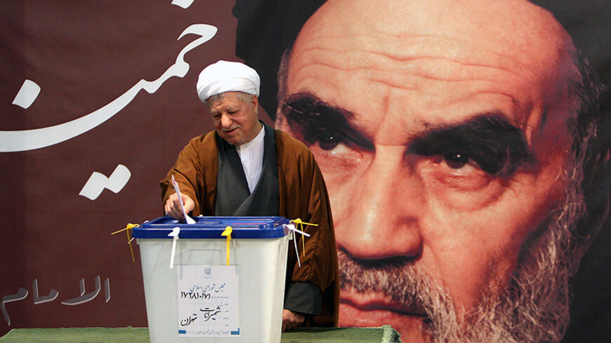 Former Iranian president Akbar Hashemi Rafsanjani casts his ballot in front of a picture of the Islamic republic's late founder Ayatollah Ruhollah Khomeini at a polling station in Tehran on March 2, 2012. Iran voted for a new parliament in the first nationwide elections since a bitterly contested 2009 poll that returned President Mahmoud Ahmadinejad to power, posing a new test of his support among conservatives. AFP PHOTO/STR        (Photo credit should read STR/AFP/GettyImages)