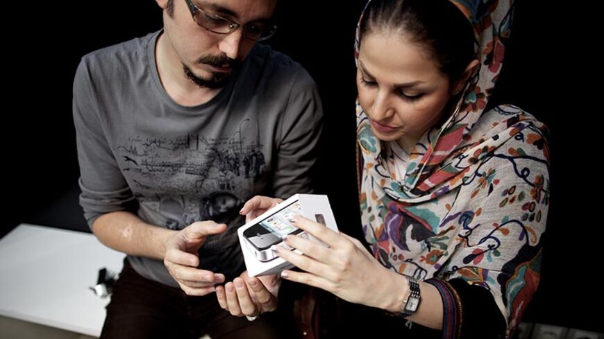 TO GO WITH AFP STORY BY MOHAMMAD DAVARI
An Iranian couple inpect the box of an IPhone they just bought at a computer shop selling Apple products in northern Tehran on June 1, 2013.  The United States lifted a ban on sales of communications equipment to Iranians and opened access to Internet services and social media, in a bid to help the Iranian people avoid government controls. The US State Department said the action will allow Iranians to skirt "attempts to silence its people by cutting off their communic