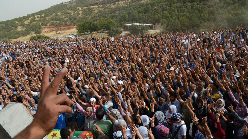 A picture taken on August 19, 2014 shows people making the victory sign as they attend the funeral ceremony of Mehdi Taskin, 24, who died during clashes that erupted between protesters and security forces during an operation to remove a statue of Mahsum Korkmazare, one of the founders of the outlawed Kurdistan Workers Party (PKK). One person was killed and two were wounded in the clashes that erupted when a group of protesters gathered at the cemetery to prevent security forces from removing the statue. Meh