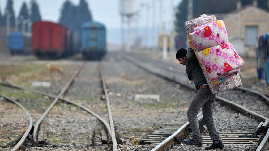 A Syrian refugee carrying his belongings passes over railway tracks after crossing the Syrian border on January 16, 2014 in Karkamis, near the town of Gaziantep, south of Turkey. Two weeks of battles between Syrian rebels and jihadists have killed at least 1,069 people, mostly fighters, the Syrian Observatory for Human Rights said Thursday. Among the dead, not all of whom were identified, were 608 Islamist and moderate rebels, 312 jihadists from the Islamic State of Iraq and the Levant (ISIL) and 130 civili