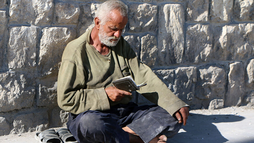 A man reads the Bible sitting in a street of the northern Syrian city of Aleppo on February 20, 2014. Syria's government forces have begun using a powerful type of cluster munition rocket not previously seen in the country's conflict, Human Rights Watch said in a statement. AFP PHOTO/ALEPPO MEDIA CENTRE/FADI AL-HALABI        (Photo credit should read Fadi al-Halabi/AFP/Getty Images)