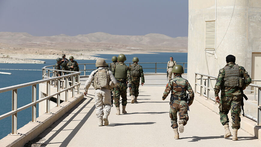 Peshmerga fighters walk on Mosul Dam in northern Iraq August 21, 2014. Iraqi and Kurdish forces recaptured Iraq's biggest dam from Islamist militants with the help of U.S. air strikes to secure a vital strategic objective in fighting that threatens to break up the country, Kurdish and U.S. officials said on Monday.  REUTERS/Youssef Boudlal (IRAQ - Tags: CIVIL UNREST POLITICS MILITARY) - RTR438VW
