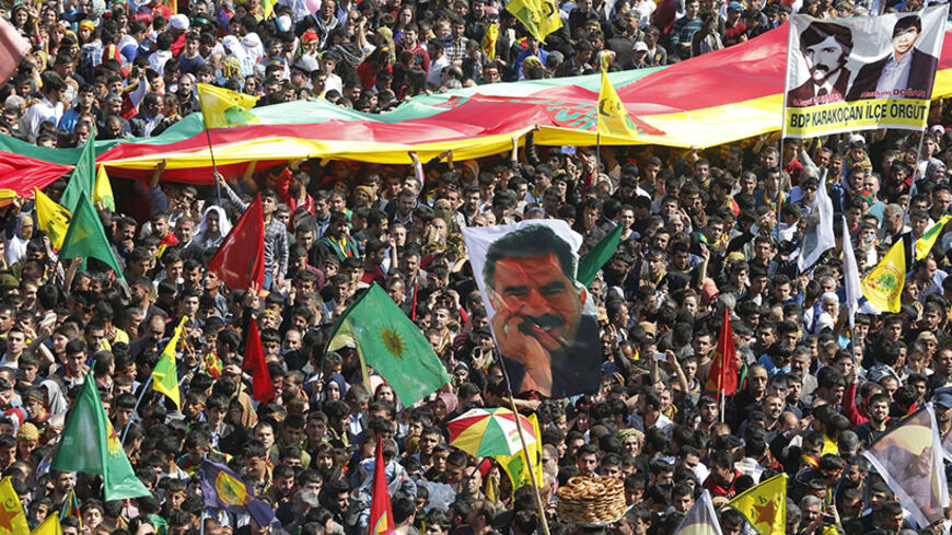 People wave Kurdish flags and hold up a picture of jailed Kurdish militant leader Abdullah Ocalan (C) of the Kurdistan Workers Party (PKK) during a gathering celebrating Newroz, which marks the arrival of spring and the new year, in Diyarbakir March 21, 2014. Ocalan called on the Turkish government on Friday to create a legal framework for their peace talks, whose fate is looking increasingly uncertain a year after he called a ceasefire by his fighters. Tens of thousands gathered in Diyarbakir, the largest 