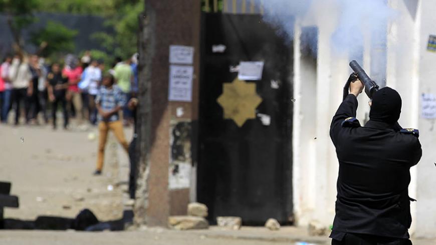 A riot police officer fires tear gas during clashes with student supporters of the Muslim Brotherhood and deposed President Mohamed Mursi at the Al-Azhar University campus in Cairo's Nasr City district, May 9, 2014. The protesters marched towards Rabaa square, closing the roads, during a demonstration by members of the Muslim Brotherhood and the pro-Mursi Anti-Coup National Alliance against the military, interior ministry and presidential candidate Abdel Fattah al-Sisi,, the former army chief who deposed th